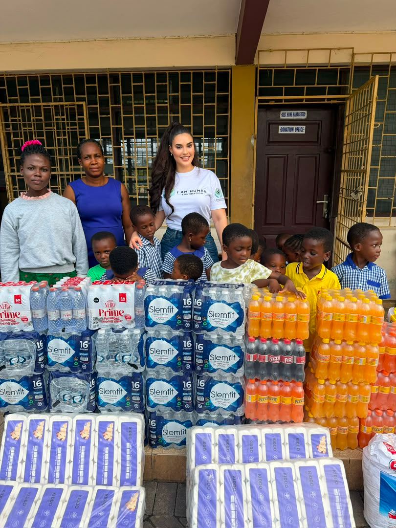 Shalimar Abbiusi and volunteers with schoolchildren behind stacked cases of donated water and supplies