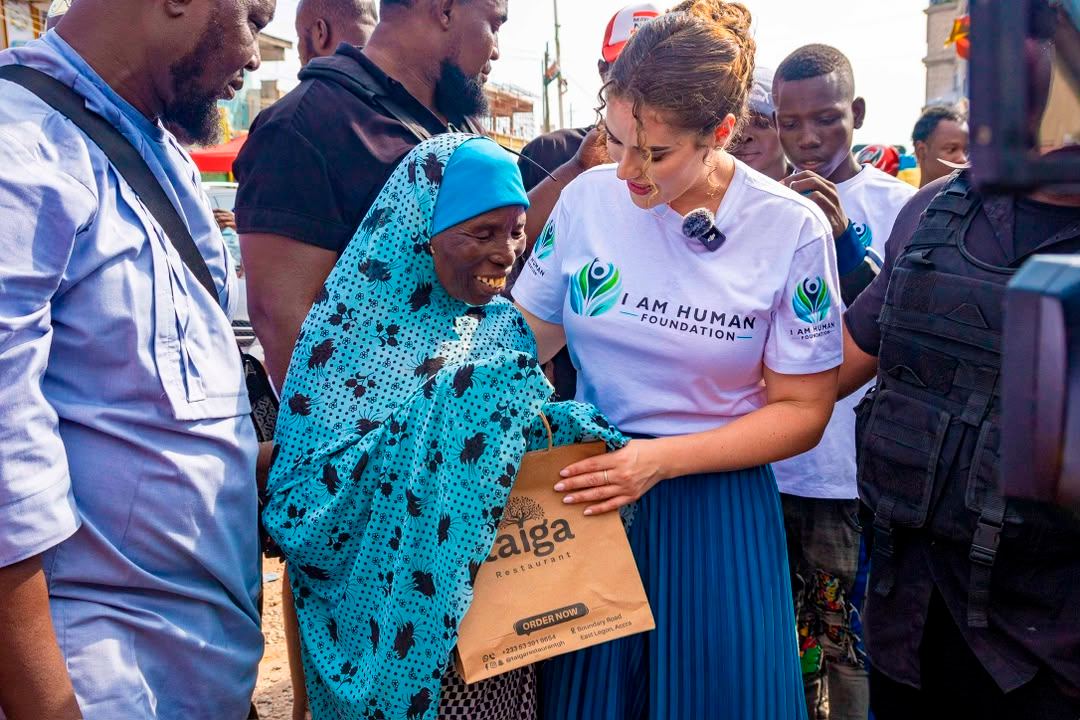 An elderly woman smiling as she receives a bag of supplies from Shalimar Abbiusi